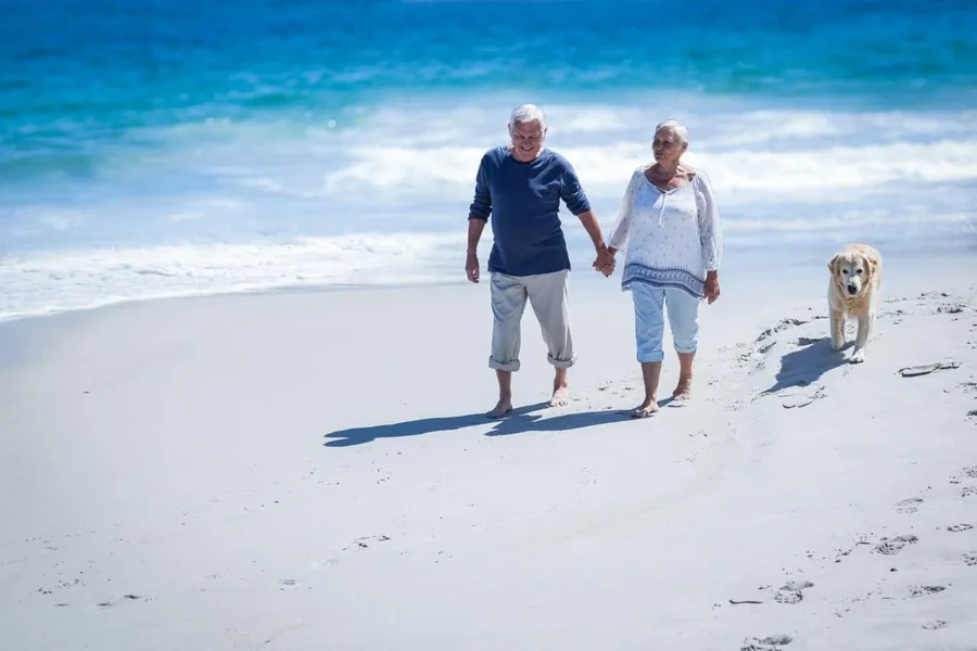 An older couple walking on a beach in the late afternoon