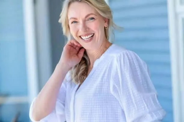 A woman in her fifties, relaxed and smiling, in natural light